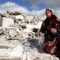 A Palestinian woman reacts as she holds the dust from the rubble of her house which was demolished by Israeli security forces, in the Palestinian village of Beit Awwa in the southwest of the West Bank on February 11, 2026. (HAZEM BADER/AFP)