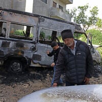 Illustrative: A Palestinian man inspects a burnt car following a reported attack by Israeli settlers in Jalud village, south of Nablus in the West Bank, on March 22, 2026. (JAAFAR ASHTIYEH/AFP)