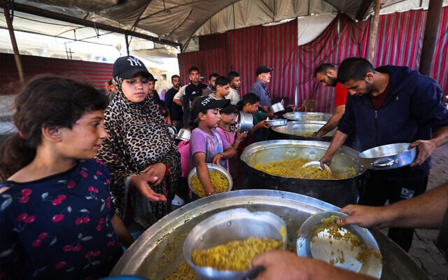 Displaced Palestinians, including women and children, gather to receive hot meals distributed by a charity kitchen in the Nuseirat camp for Palestinian refugees in the Central Gaza Strip on June 12, 2026 (Eyad Baba/AFP)