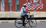 A cyclist rides past a billboard bearing pictures of Iran's late supreme leader Ayatollah Ali Khamenei, along a street in Baghdad on July 2, 2026, ahead of his funeral in Tehran. (Ahmad al-Rubate/AFP)
