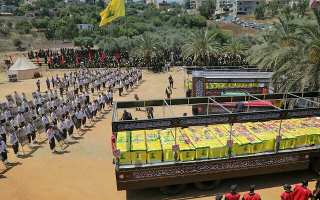 The caskets of Hezbollah fighters killed during clashes with the Israeli army are pictured to the right and left of a mock coffin of Iran’s slain supreme leader, Ayatollah Ali Khamenei during a mass funeral in the southern Lebanese village of Majdel Selm on July 18, 2026 (Ibrahim AMRO/AFP)