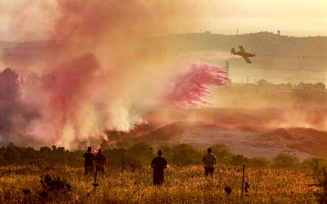Palestinians watch as an Israeli firefighting plane extinguishes a blaze near the village of Tell, adjacent to the Israeli settlement of Havat Gilad, west of Nablus in the West Bank on July 18, 2026. (Jaafar ASHTIYEH/AFP)