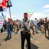 An armed student waves a Yemeni flag as he is flanked by a peer waving a Palestinian flag and others displaying the Houthi rebels' banner, which reads 'Death to America, death to Israel, a curse on the Jews,' at a rally in support of the Iran-backed rebels amid escalating tensions with Saudi Arabia, on the Sanaa University Campus in the Houthi-held Yemeni capital, on July 22, 2026. (Mohammed HUWAIS/AFP)