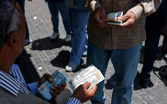 A street money changer exchanges currency in Ramallah, in the West Bank, on July 23, 2026. (Zain JAAFAR/AFP)