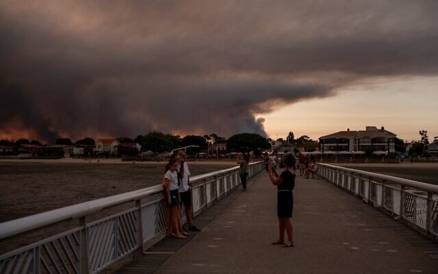 People on the beach in Andernos-Les Bains during a fire in Lege Cap-Ferret forest, southwestern France, on July 23, 2026, as part of the nearby area has been evacuated. (Olivier MORIN/AFP)