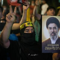 A Hezbollah supporter flashes a victory sign while holding a poster of Iranian Supreme Leader Mojtaba Khamenei during a gathering against the US-Israeli military operation with Iran and its allies in Dahiyeh, Lebanon, Wednesday, June 10, 2026. (AP Photo/Bilal Hussein)