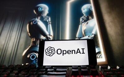 The OpenAI logo is displayed on a cellphone with an image on a computer monitor generated by ChatGPT’s Dall-E text-to-image model, December 8, 2023, in Boston. (AP Photo/Michael Dwyer)