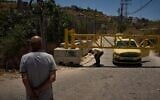 A Palestinian man bends down to cross a closed gate after the Israeli army imposed a closure on the entrances of the West Bank village of Sinjil, July 1, 2026. (AP/Leo Correa)