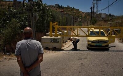 A Palestinian man bends down to cross a closed gate after the Israeli army imposed a closure on the entrances of the West Bank village of Sinjil, July 1, 2026. (AP/Leo Correa) A Palestinian man bends down to cross a closed gate after the Israeli army imposed a closure on the entrances of the West Bank village of Sinjil, July 1, 2026. (AP/Leo Correa)