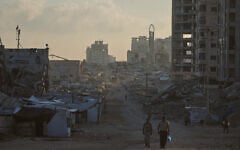 Palestinians walk along a street surrounded by buildings destroyed in Israeli military strikes during the Israel-Hamas war, in Gaza City, Thursday, July 2, 2026. (AP Photo/Jehad Alshrafi)