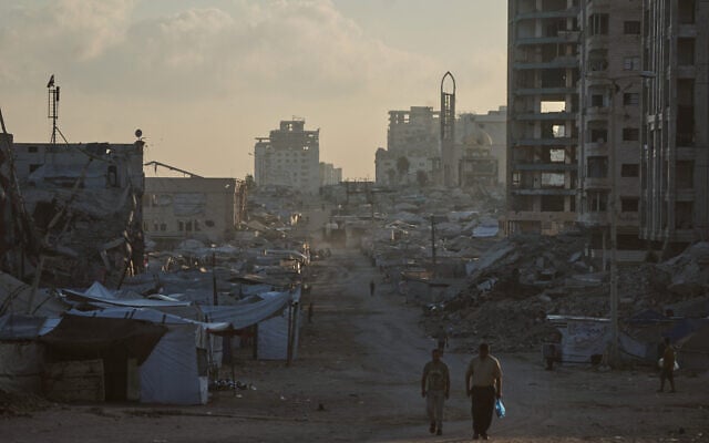 Palestinians walk along a street surrounded by buildings destroyed in Israeli military strikes during the Israel-Hamas war, in Gaza City, Thursday, July 2, 2026. (AP/Jehad Alshrafi)