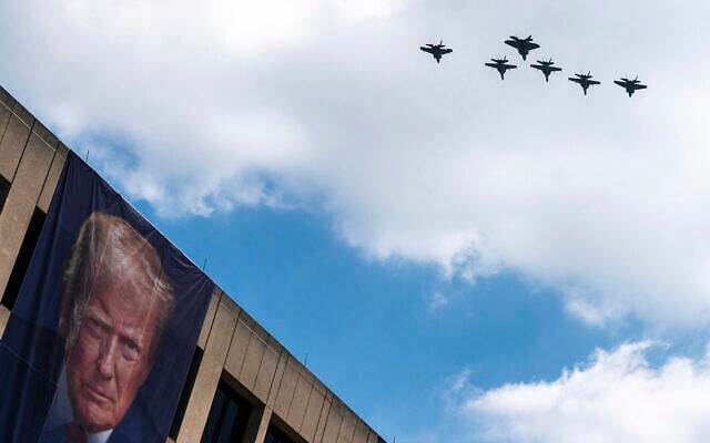 A flight of F-18s, F-35s and a F-22 fly past a picture of US President Donald Trump hanging on the US Department of Labor near the Great American State Fair on the National Mall, July 3, 2026, in Washington. (AP Photo/Nathan Howard)