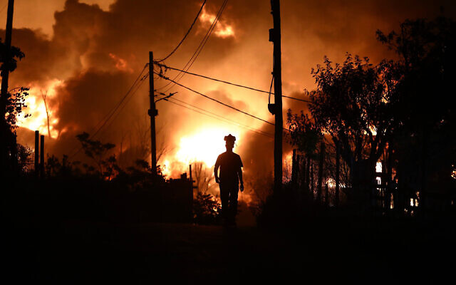 A man with a respirator mask on his head is silhouetted during a wildfire on the outskirts of the northern city of Thessaloniki, Greece, July 5, 2026. (AP Photo/Giannis Papanikos) A man with a respirator mask on his head is silhouetted during a wildfire on the outskirts of the northern city of Thessaloniki, Greece, July 5, 2026. (AP Photo/Giannis Papanikos)