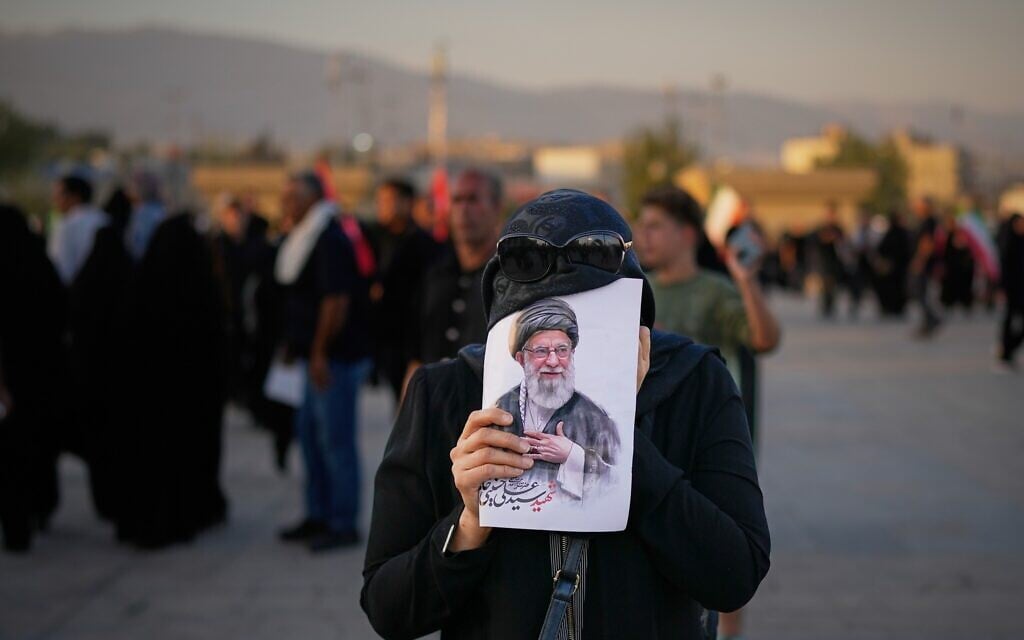 A woman covers her face with a picture of slain Iranian Supreme Leader Ayatollah Ali Khamenei as mourners gather during funeral ceremonies at the Imam Khomeini Mosalla Grand Mosque in Tehran, Iran, Sunday, July 5, 2026. (AP Photo/Altaf Qadri)