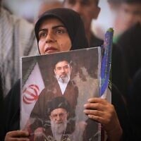 A mourner holds a portrait depicting Iran's Supreme Leader Ayatollah Mojtaba Khamenei, top, and his late father, Ayatollah Ali Khamenei, during a funeral procession for the elder Khamenei inside the Imam Ali Shrine in Najaf, Iraq, July 8, 2026. (AP/Hadi Mizban)