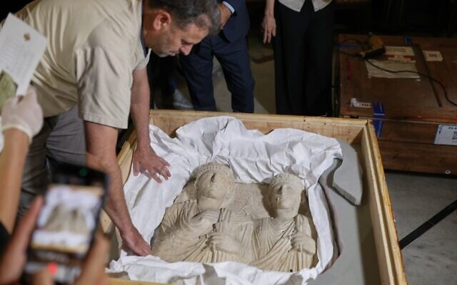 A museum employee opens a crate containing Palmyrene funerary reliefs that once adorned the walls of tombs and date to the second and third centuries AD after Syrian authorities unveiled antiquities returned from France at the National Museum in Damascus, Syria, July 8, 2026.(AP Photo/Ghaith Alsayed)