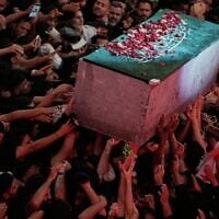 The flower petal-covered coffin of the late Iranian supreme leader ayatollah Ali Khamenei is carried above mourners reaching out to touch it outside the Imam Hussein Shrine in Karbala, Iraq, July 9, 2026. (AP/Khalil Hamra)