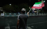 A pro-government demonstrator waves an Iranian flag in a gathering commemorating the late Iranian Supreme Leader Ayatollah Ali Khamenei at a square in Tehran, Iran, July 11, 2026. (AP Photo/Vahid Salemi)