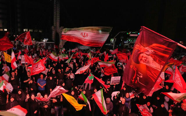 Pro-government demonstrators wave Iranian and religious flags in a gathering commemorating the late Iranian supreme leader Ayatollah Ali Khamenei, shown in a flag at right, at a square in Tehran, July 11, 2026 (AP/Vahid Salemi) Pro-government demonstrators wave Iranian and religious flags in a gathering commemorating the late Iranian supreme leader Ayatollah Ali Khamenei, shown in a flag at right, at a square in Tehran, July 11, 2026 (AP/Vahid Salemi)