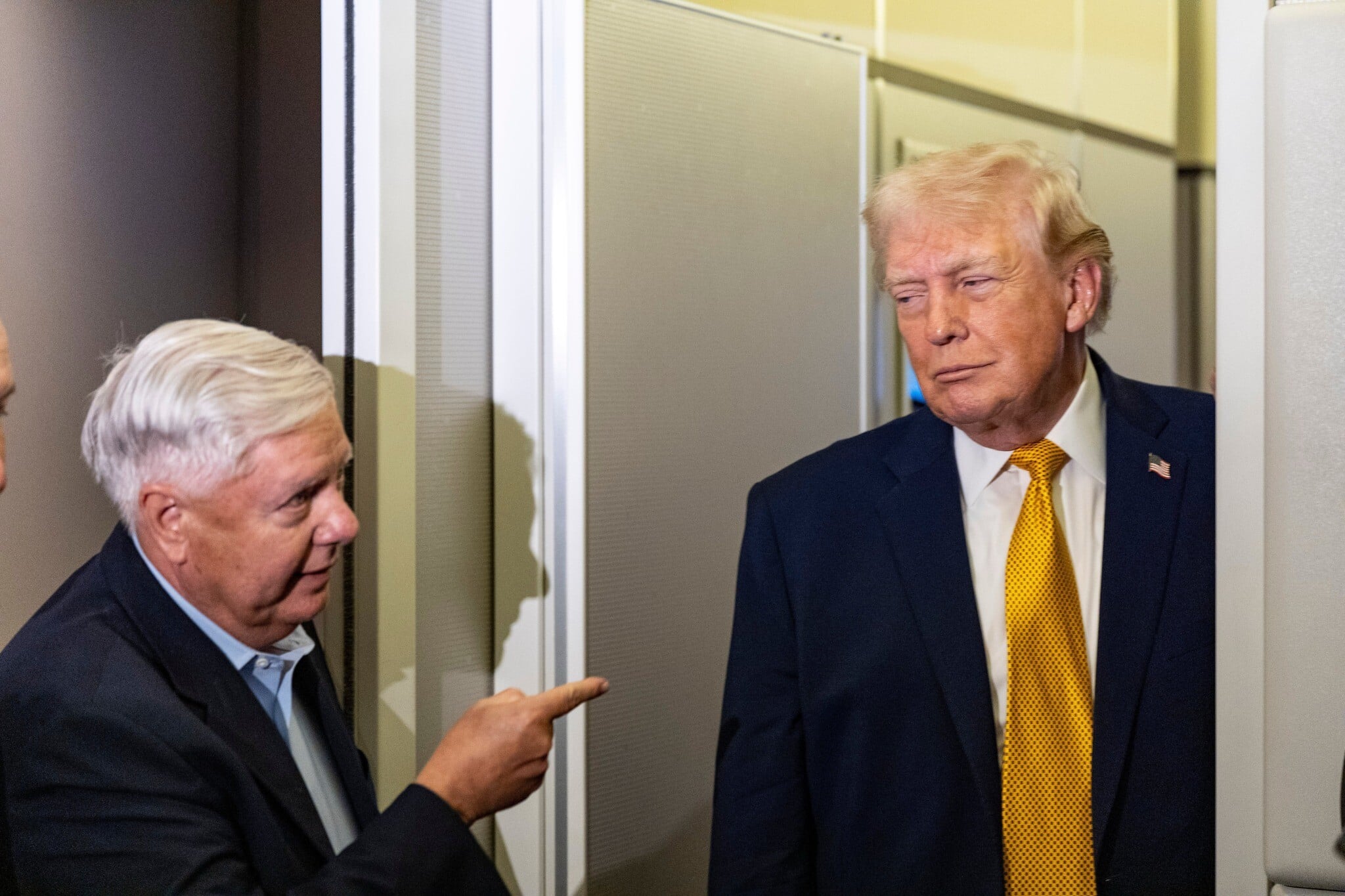 Sen. Lindsey Graham, left, gestures as US President Donald Trump speaks with reporters while in flight on Air Force One, on January 4, 2026, as they…