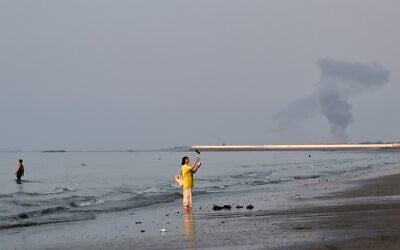 A woman stands at the water's edge along the Strait of Hormuz as a plume of smoke rises in the background following an explosion, off Bandar Abbas, Iran, July 13, 2026. (Razieh Poudat/ISNA via AP) A woman stands at the water's edge along the Strait of Hormuz as a plume of smoke rises in the background following an explosion, off Bandar Abbas, Iran, July 13, 2026. (Razieh Poudat/ISNA via AP)