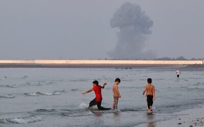 Three boys play in the shallow waters of the Strait of Hormuz, as a plume of smoke rises from an explosion in the background, off Bandar Abbas, Iran, July 13, 2026. (Razieh Poudat/ISNA via AP) Three boys play in the shallow waters of the Strait of Hormuz, as a plume of smoke rises from an explosion in the background, off Bandar Abbas, Iran, July 13, 2026. (Razieh Poudat/ISNA via AP)