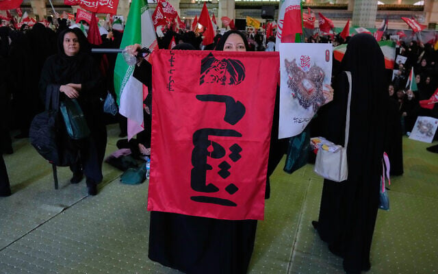 A mourner displays a flag with a portrait of the late Supreme Leader Ayatollah Ali Khamenei and a word which reads in Farsi: “Revenge” in a ceremony commemorating the late leader at the Imam Khomeini Mosalla Grand Mosque in Tehran, July 14, 2026 (AP Photo/Vahid Salemi)