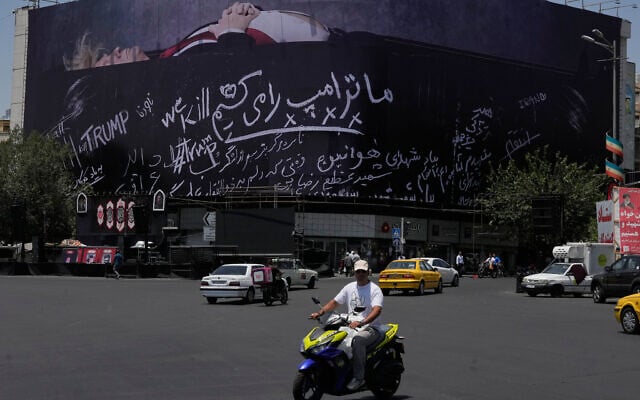 Vehicles drive past a billboard depicting US President Donald Trump lying on what appears to be a coffin and bearing anti-Trump messages, including the phrase 'We Kill Trump,' at Islamic Revolution Square in downtown Tehran, Iran, July 15, 2026. (AP/Vahid Salemi)