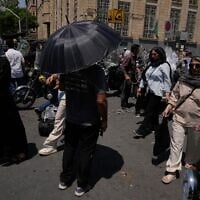 A man shelters from the sun under an umbrella as he stands at an intersection around Tehran’s traditional main bazaar, Iran, July 16, 2026 (AP Photo/Vahid Salemi)