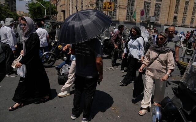 A man shelters from the sun under an umbrella as he stands at an intersection around Tehran’s traditional main bazaar, Iran, July 16, 2026 (AP Photo/Vahid Salemi)