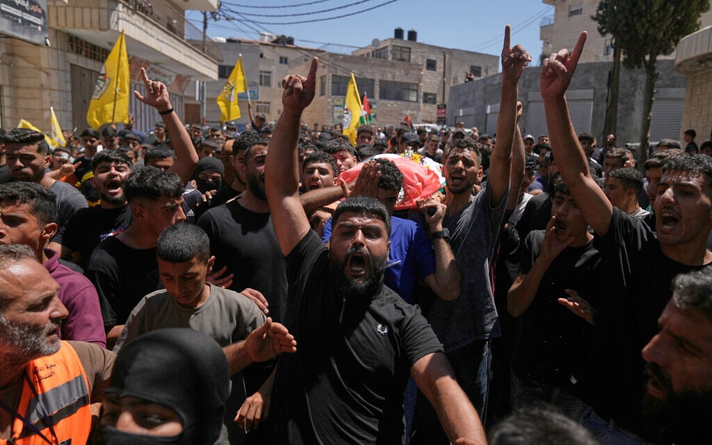 Mourners carry the body of Palestinian Fadi Na’asan, 17, who succumbed to his wounds sustained during clashes with Israeli army soldiers last Saturday, during his funeral in the West Bank village of al-Mughayyir, July 18, 2026. (AP/Majdi Mohammed)