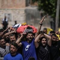 Mourners carry the body of Palestinian Fadi al-Naasan, 17, who succumbed to his wounds sustained during clashes with Israeli soldiers, during his funeral in the West Bank village of al-Mughayyir, July 18, 2026. (AP/Majdi Mohammed)