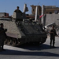 Lebanese soldiers stand beside an armored personnel carrier near buildings damaged during the Israel-Hezbollah war in Ghandouriyeh village, southern Lebanon, July 21, 2026. (Hassan Ammar/AP)