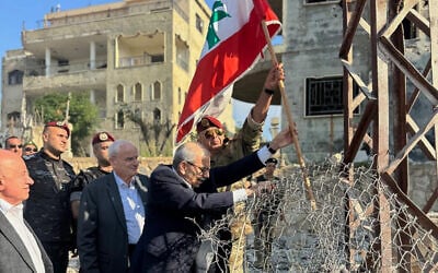 In this photo released by the Lebanese Government press office, Lebanese Prime Minister Nawaf Salam, center, raises a Lebanese flag during a visit to the southern village of Zawtar Al Gharbieh, Lebanon, July 22, 2026. (Lebanese Government press office via AP)