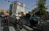 A man rides on his motorbike as boys ride on their bicycles in downtown Tehran, Iran, July 22, 2026. (AP/Vahid Salemi)