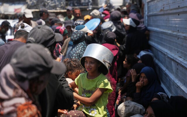 Displaced Palestinians line up to receive donated food at a community kitchen in Khan Younis, southern Gaza Strip, July 23, 2026. (AP Photo/Abdel Kareem Hana)