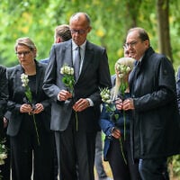From left, Family Minister Karin Prien, Justice Minister Stefanie Hubig, German Chancellor Friedrich Merz, and German Interior Minister Alexander Dobrindt carry flowers as they visit Tiergarten park after an attacker rammed a vehicle into a crowd near Berlin’s annual Pride event, in Berlin, July 26, 2026. (Annegret Hilse/Pool Photo via AP)