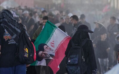 Iranian Shi'ite pilgrims carrying Iranian flags arrive at the Al-Mundheriya border crossing to join millions of Muslims heading to the holy city of Karbala for the annual Arbaeen pilgrimage, in Diyala, Iraq, July 27, 2026. (AP Photo/Hadi Mizban)