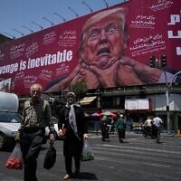 Pedestrians walk past a billboard depicting US President Donald Trump being grabbed by the neck alongside the message, 'Revenge is inevitable' in English and Farsi, in Tehran, Iran, July 27, 2026. (AP Photo/Vahid Salemi)