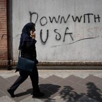 A woman talks on her cellphone as she walks past an anti-US graffiti on the wall of the British Embassy in Tehran, Iran, July 27, 2026. (AP Photo/Vahid Salemi)