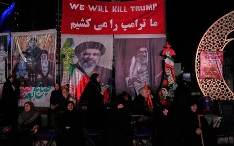 Iranian pro-government demonstrators sit beneath a banner reading in English and Farsi, “We will kill Trump,” during a pro-government gathering at a square in Tehran, Iran, July 28, 2026. (AP/Vahid Salemi)