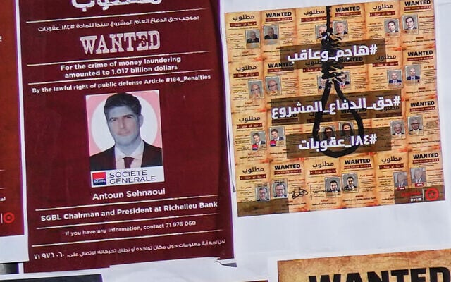 A mock 'wanted' poster of Lebanese bank owner Antoun Sehnaoui, left, plastered by protesters outside the Lebanese Central Bank, in Beirut, Lebanon, January 19, 2024. (AP/Hussein Malla)