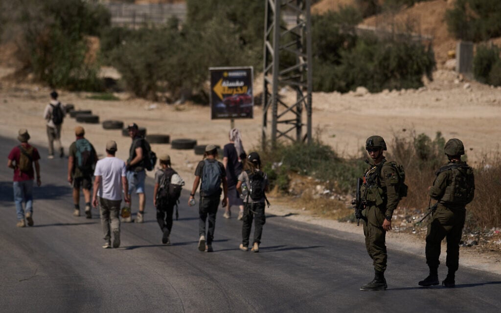 Members of the Israeli forces stand in guard on a road as Israeli settlers march through the Palestinian village of Sarra, near the West Bank city of Nablus, July 31, 2026. (AP/Leo Correa)
