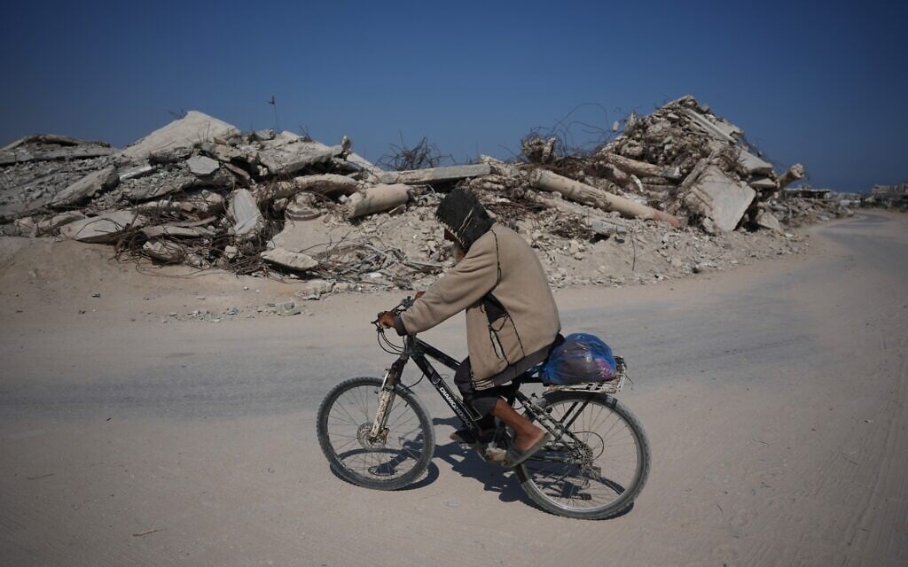 A Palestinian man rides his bicycle by the rubble of buildings that were destroyed during the Israel Hamas war, in Khan Younis, southern Gaza Strip, July 31, 2026. (AP Photo/Abdel Kareem Hana)