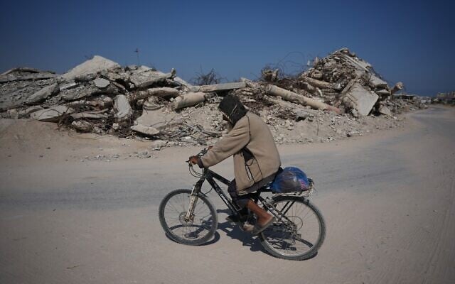 A Palestinian man rides his bicycle by the rubble of buildings that were destroyed during the Israel Hamas war, in Khan Younis, southern Gaza Strip, July 31, 2026. (AP Photo/Abdel Kareem Hana)
