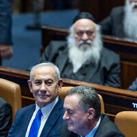 Prime Minister Benjamin Netanyahu (center), Justice Minister Yariv Levin (left), and Defense Minister Israel Katz (right), with ultra-Orthodox MKs Yitzchak Goldknopf, Moshe Gafni and Meir Porush behind them, seen in the Knesset shortly before the vote on a law banning arrests of ultra-Orthodox draft dodgers and legitimizing ongoing mass ultra-Orthodox non-enlistment, July 14, 2026. (Chaim Goldberg/Flash90)