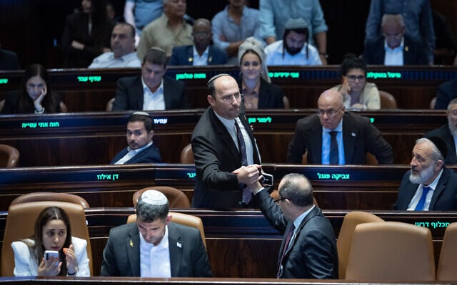 Religious Zionism MK Simcha Rothman celebrates with ministers and fellow lawmakers following the passage of a bill to split the duties and powers currently held by the attorney general between two separate officeholders, at the plenum hall of the Knesset in Jerusalem on July 15, 2026. (Yonatan Sindel/Flash90)