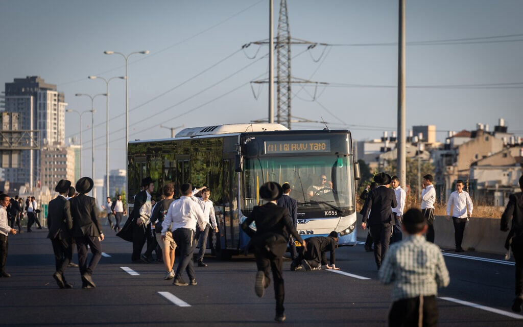Ultra-Orthodox Jewish men block a road during a protest against the jailing of draft dodgers on Route 4 near Bnei Brak, July 16, 2026. (Chaim Goldberg/Flash90)