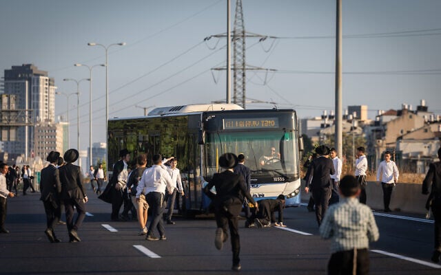 Ultra-Orthodox Jewish men block a road during a protest against the jailing of draft dodgers on Route 4 near Bnei Brak, July 16, 2026. (Chaim Goldberg/Flash90)