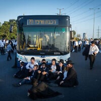 Ultra-Orthodox Jewish men block a bus on Route 4, near Bnei Brak, during a demonstration against the arrest of draft evaders, on July 16, 2026. (Chaim Goldberg/Flash90)